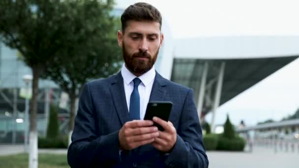 Businessman using smartphone and smiling at airport. Young business executive with mobile phone at airport. - Footage, Video