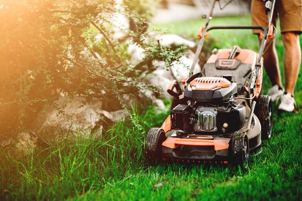 Gardening details, industrial gardener using lawnmower and cutting grass in garde - Foto, imagen