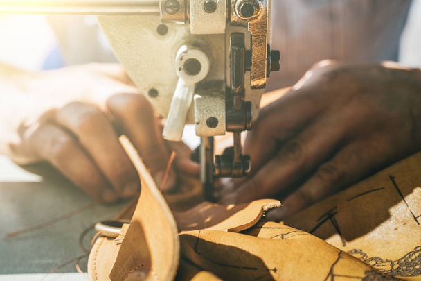 Arbeitsprozess des Lederhandwerkers. Gerber oder Häuterin näht Leder auf einer speziellen Nähmaschine, Nahaufnahme - Foto, Bild