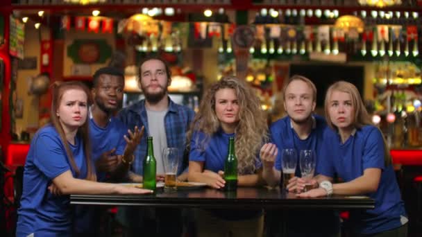 Emotionele fans in blauwe shirts bij een bierbar. Een multi-etnische groep van Afro-Amerikaanse mensen is boos en verdrietig vanwege het falen van hun team. Nederlaag van je favoriete voetbal, volleybal, - Video