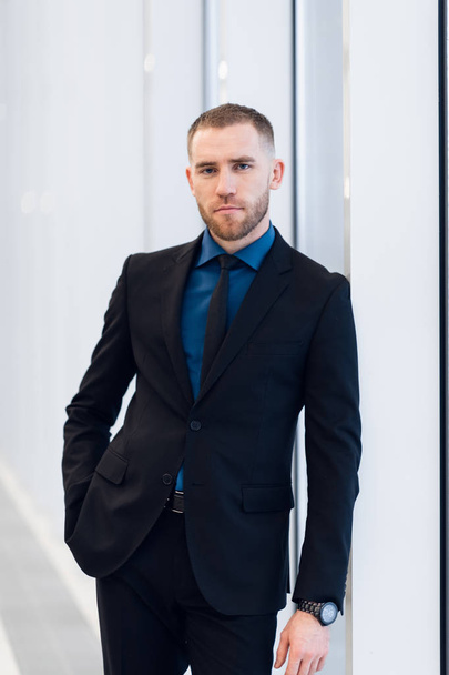 Portrait of handsome man standing in a suit and tie in front of glass door - Fotó, kép