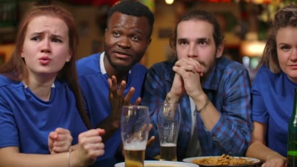 Close-up groep van fans emotioneel kijken naar een sport uitgezonden in een bar op TV met bier, mannen en vrouwen in blauwe T-shirts verheugen en knuffel, het vieren van een doel gescoord door hun voetbal, voetbalteam - Video