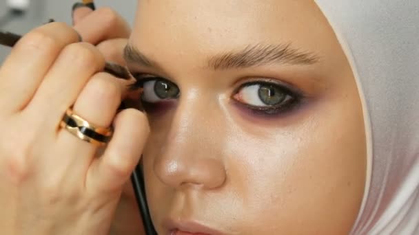 Woman make-up artist stylist makes makeup fashionable pink smoky eyes with special makeup brush of young model - Video