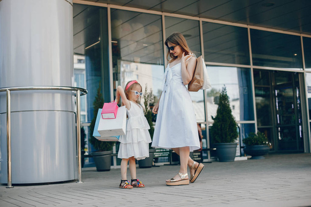 Mother and daughter with shopping bag in a city - 写真・画像