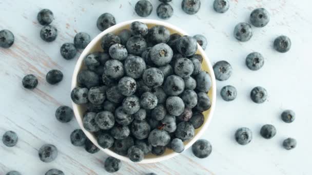 Verse Blueberry in witte plaat op blauw hout textuur oppervlak. Bovenaanzicht 4k-beeldmateriaal. - Video