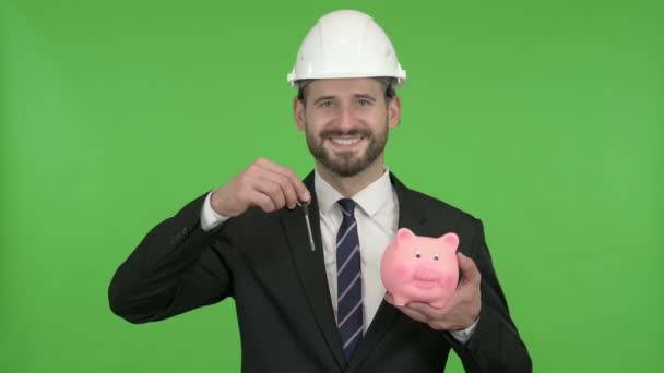 glücklicher Ingenieur hält Sparschwein mit Hausschlüssel gegen Chromaschlüssel - Filmmaterial, Video
