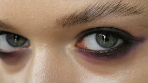 Velmi módní. Umělec, který dělá profesionální make-up zakouřené oči růžové a černé barvy pro dívčí model pro natáčení ve studiu. Zavřít pohled na model zeleného oka - Záběry, video