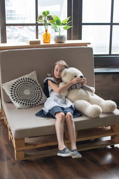 hübsches kleines Mädchen flüstert Teddybär zu und lächelt - Foto, Bild