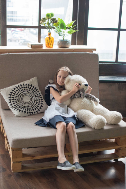 hübsches kleines Mädchen flüstert Teddybär zu und lächelt - Foto, Bild
