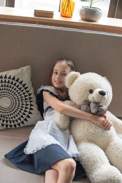 Pretty little girl is whispering to teddy bear and smiling - Foto, Bild