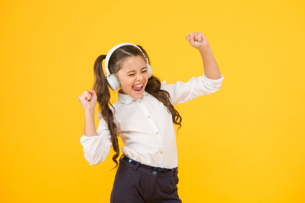 Singing in tune. Cute small child taking her singing lessons on yellow background. Adorable little girl singing her favorite song playing in earphones. The voice singing school - Foto, afbeelding