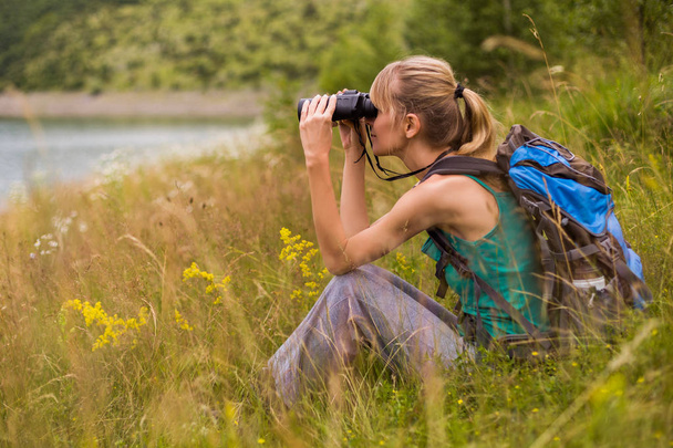 Woman hiker using binoculars while spending time in the beautiful nature. - Photo, Image