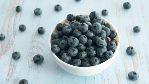 Verse Blueberry in witte plaat op blauw hout textuur oppervlak. 4k-beeldmateriaal. - Video