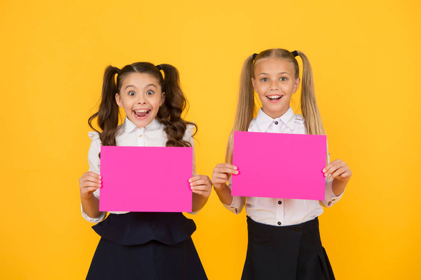 Visual communication concept. School friendship. Girls school uniform hold poster. School girls show poster. Social poster copy space. Socialization involves how children get along with each other - Foto, imagen