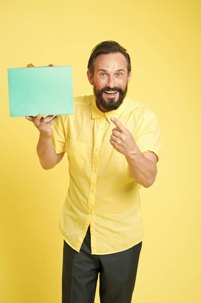 Sale and discount. Online shopping. Profitable purchase. Shop assistant or sales expert. Shopping happiness. Man emotional enjoying shopping. Bearded mature man with shopping bag on yellow background - Фото, зображення