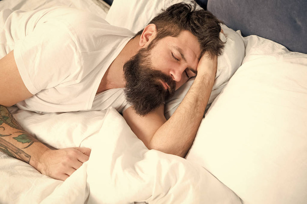 Sleep disorders concept. Man bearded hipster having problems with sleep. Guy lying in bed try to relax and fall asleep. Relaxation techniques. Violations of sleep and wakefulness. Need some rest - Фото, изображение