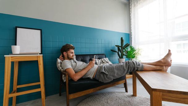 Mannen spelen een laptop met een kopje koffie in de woonkamer. - Foto, afbeelding