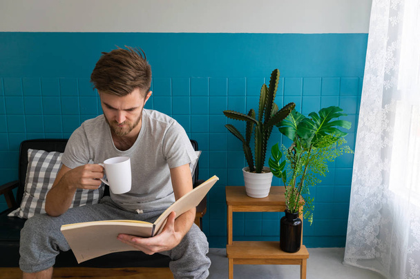 Οι άντρες διαβάζουν βιβλία με κούπες καφέ στο σαλόνι. - Φωτογραφία, εικόνα