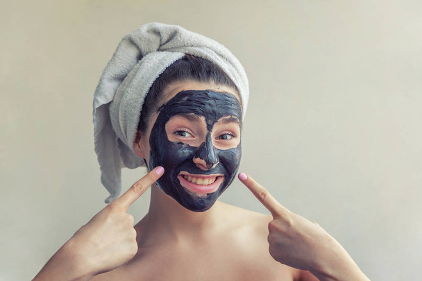 Woman applying black nourishing mask on face - Photo, Image