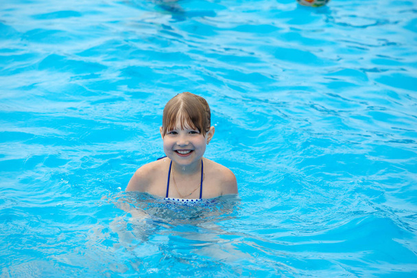 プールで泳いでいるの幸せな女の子 - 写真・画像