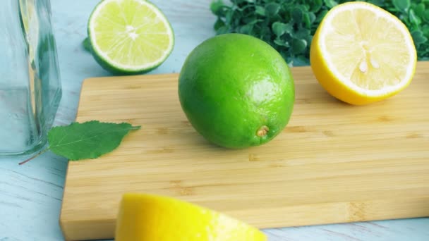 Gesneden limoen en citroen op houten keuken oppervlak met glas. 4k-beeldmateriaal close-up. - Video