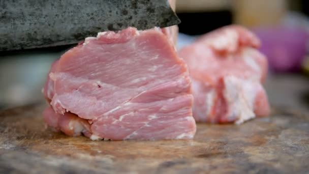 Handen van vrouwen met behulp van een keukenmes gesneden varkensvlees op de snijplank voor gekookt. - Video