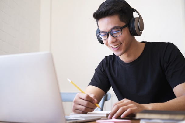 Молодий студент навчається вдома, використовуючи ноутбук та навчаючись онлайн
 - Фото, зображення
