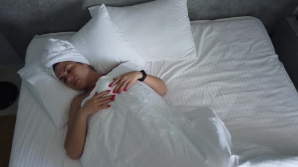 Beautiful young girl is sleeping on a white pillow. She is waking up, stretching and smiling. Handheld real time medium shot - Filmmaterial, Video