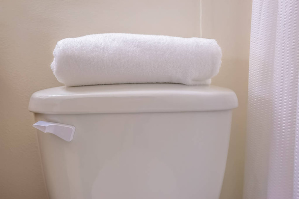 Primo piano del serbatoio di una toilette con un asciugamano bianco piegato sulla parte superiore del coperchio
 - Foto, immagini