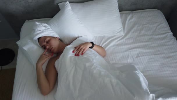 Beautiful young girl is sleeping on a white pillow. She is waking up, stretching and smiling. Handheld real time medium shot - Séquence, vidéo