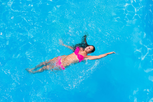 A girl is relaxing in a swimming pool - Foto, afbeelding