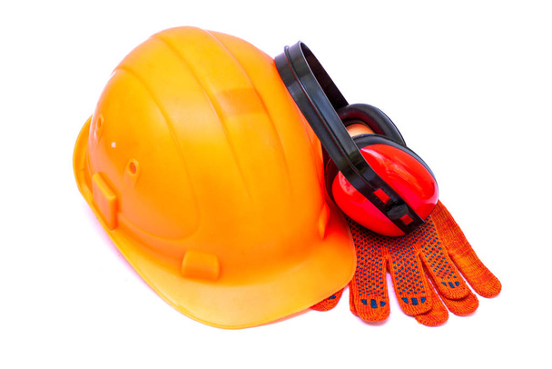 白い背景の建設現場での保護手段としてビルダーのためのオレンジ色のヘルメット. - 写真・画像