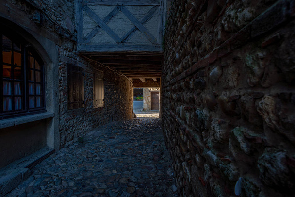 Dark passageway leading to a sunny street, Perouges, France - Fotó, kép