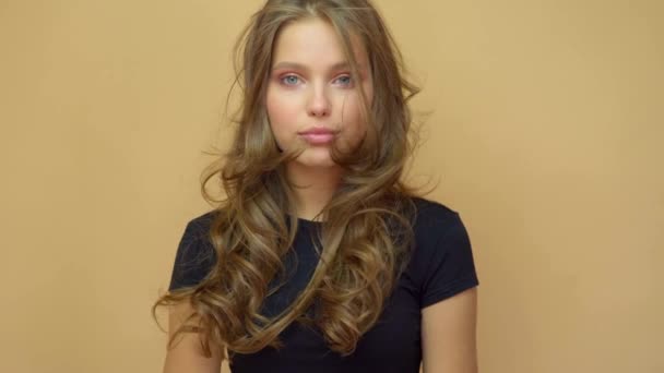 closeup portrait of young wooman posing to a camera with blowed out hair on grey - Кадри, відео