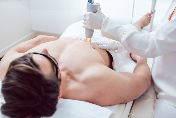 Cosmetologist using laser to remove chest hair of man - Φωτογραφία, εικόνα