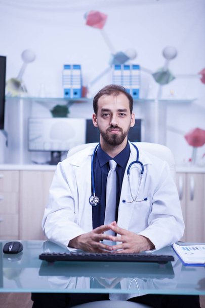 Young and inteligent doctor in his cabinet wearing a white coat and his stethoscope - Foto, Imagem