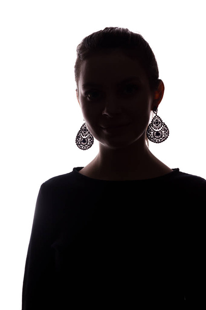 Young girl with earrings looks straight ahead, portrait isolate silhouette - Photo, Image
