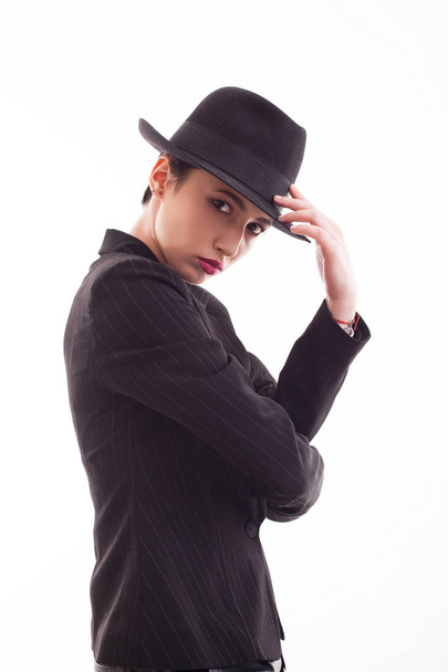 Glamorous female posing in studio wearing a black jacket with a stylish hat - Zdjęcie, obraz