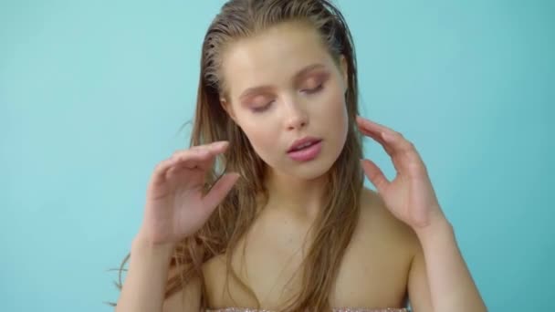 Portrait of sensual beautiful young woman with blue grey eyes looking at camera in a light blue background. - Materiał filmowy, wideo