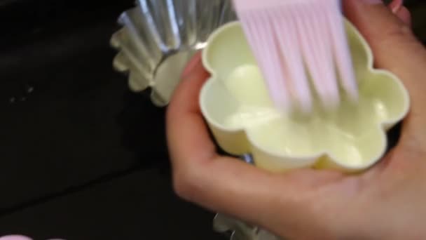 A woman lubricates silicone cake baking dishes. Uses a pastry brush. Close-up. Cooking a dessert. - Záběry, video