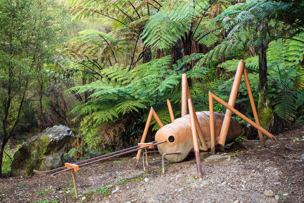 Sculpture d'une weta (un insecte géant néo-zélandais) entourée d'une forêt
  - Photo, image