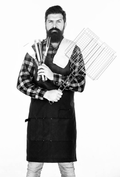 Barbecue season. Bearded hipster wear apron for barbecue. Roasting and grilling food. Man hold cooking utensils barbecue. Tools for roasting meat outdoors. Picnic and barbecue. Tips for cooking meat - Fotó, kép