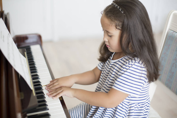 Kazakh asian little girl learning to play piano - Photo, Image
