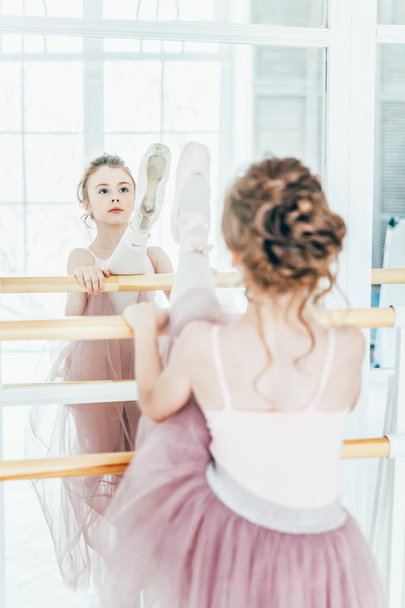 ダンスクラスでピンクのチュチュスカートで美しい優雅なバレリーナ練習バレエの位置 - 写真・画像