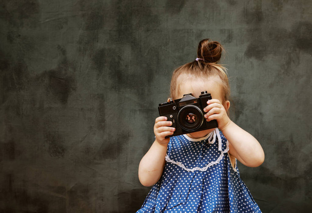 美しいドレスの小さな女の子は写真を撮ることを学ぶ - 写真・画像