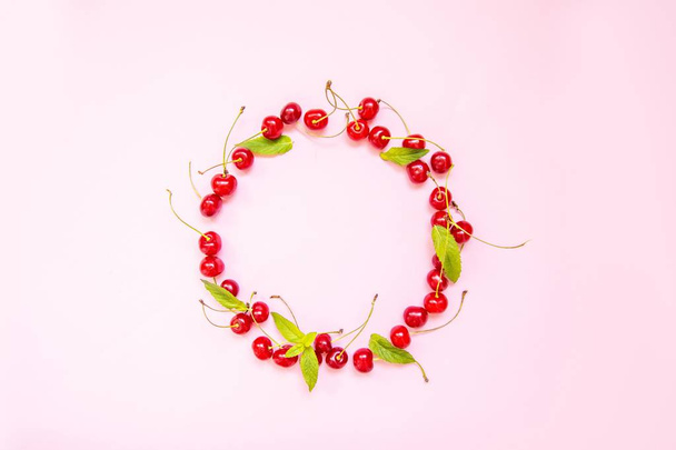 Frame made of sweet cherries on light on a pink background. Minimalism, flat lay, top view, design. - Foto, Imagem