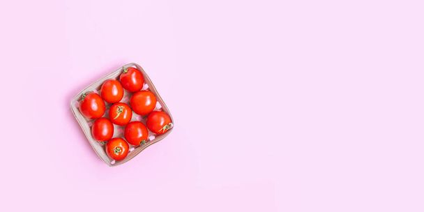 Свіжі стиглі червоні помідори в дерев'яному кошику на рожевому тлі з місцем для тексту
 - Фото, зображення