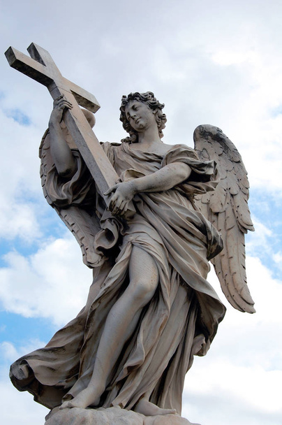 Статуя ангела, стоящего на мосту, ведущем к замку Сант-Анджело против голубого неба, Рим
 - Фото, изображение