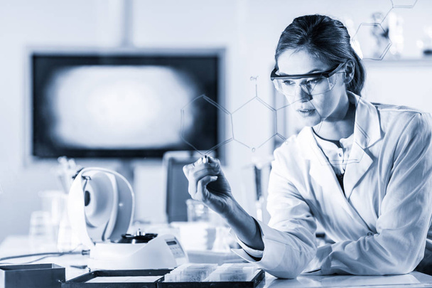 Muotokuva luottavainen naispuolinen tutkija biotieteiden laboratoriossa kirjallisesti rakenteellinen kemiallinen kaava lasi aluksella. - Valokuva, kuva