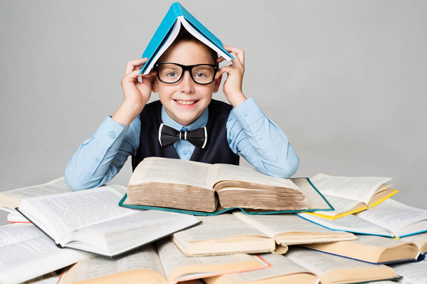 Happy Child Reading Many Books with Book on Head, Funny School Boy - 写真・画像